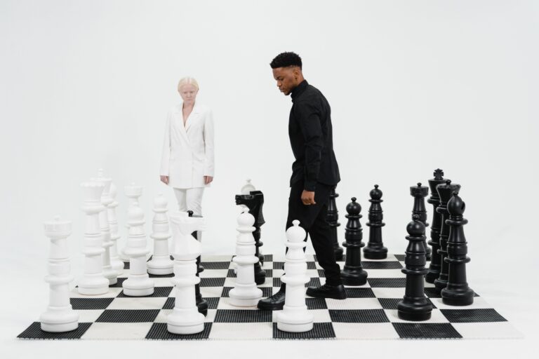 Two people facing off on a giant chessboard, black vs white