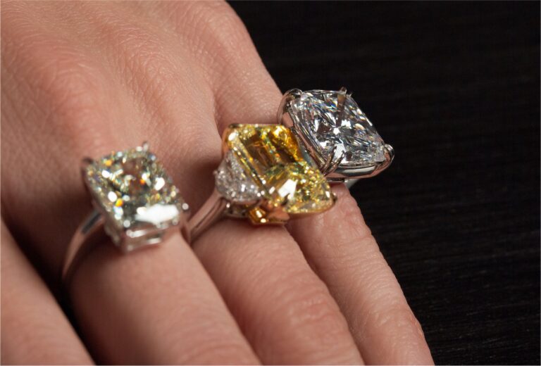 Three large diamond solitaire engagement rings including a fancy yellow diamond on a hand