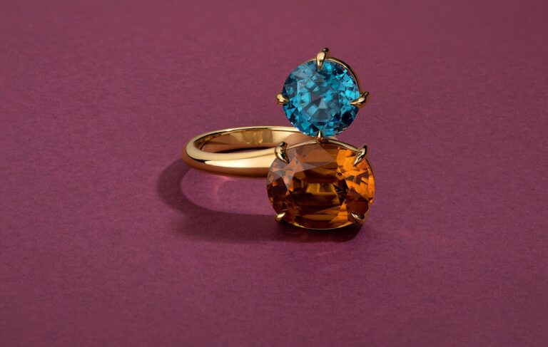 Gold toi et moi ring with blue topaz and citrine gemstones on magenta background