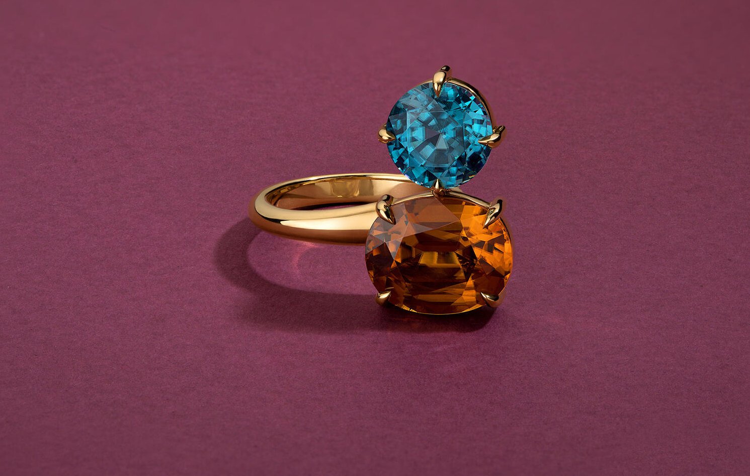 Gold toi et moi ring with blue topaz and citrine gemstones on magenta background