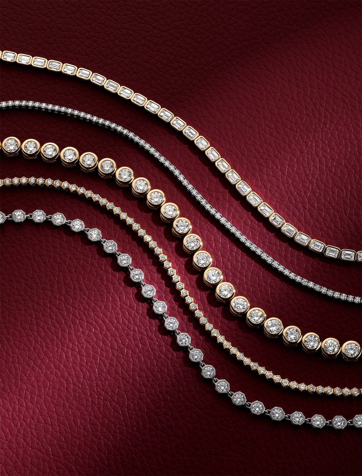 Diamond tennis bracelets in mixed metals arranged on burgundy leather