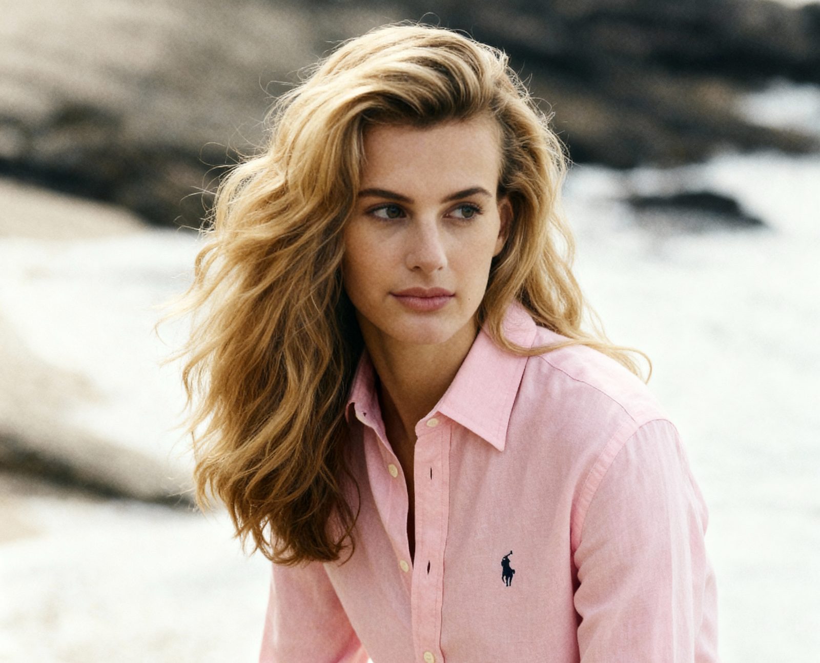 AI-generated on-model fashion lifestyle photo of a pink shirt by the sea, produced by Tuple Strategy